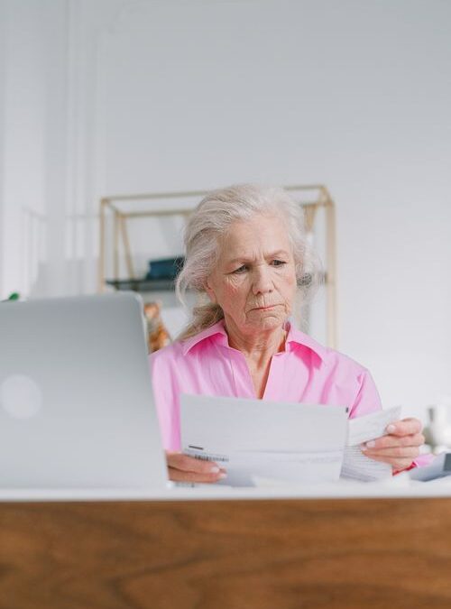 mujer mayor revisando documentos de su plan de salud en casa