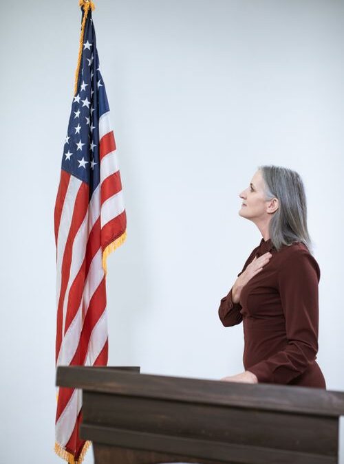 mujer mayor prometiendo lealtad junto a la bandera de Estados Unidos