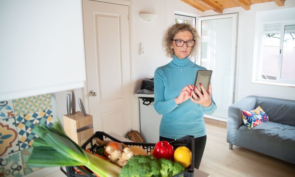 Mujer mayor revisa su teléfono en la cocina de su casa