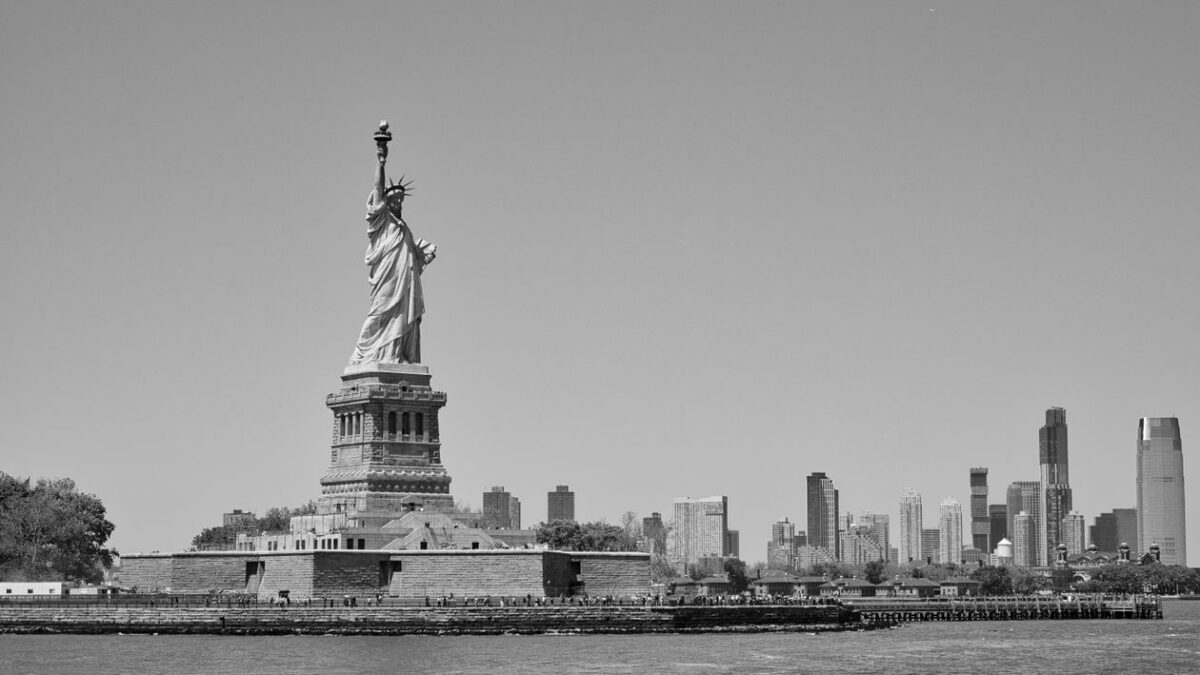 Estatua de la Libertad en blanco y negro con el horizonte de la ciudad de Nueva York al fondo