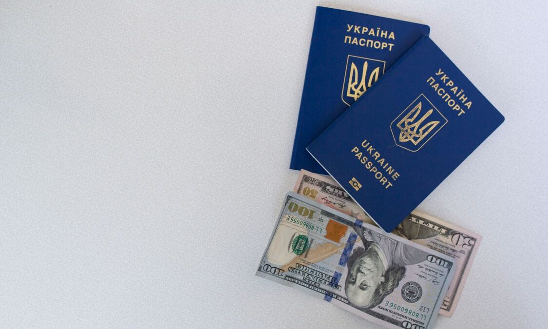 Pasaportes ucranianos y billetes de dólar sobre una superficie blanca