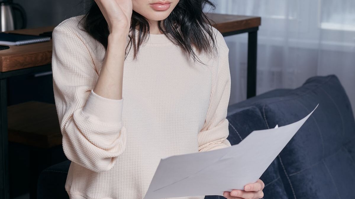 Mujer preocupada leyendo documentos en su casa