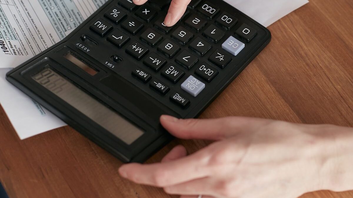 Persona calculando con una calculadora y documentos sobre un escritorio