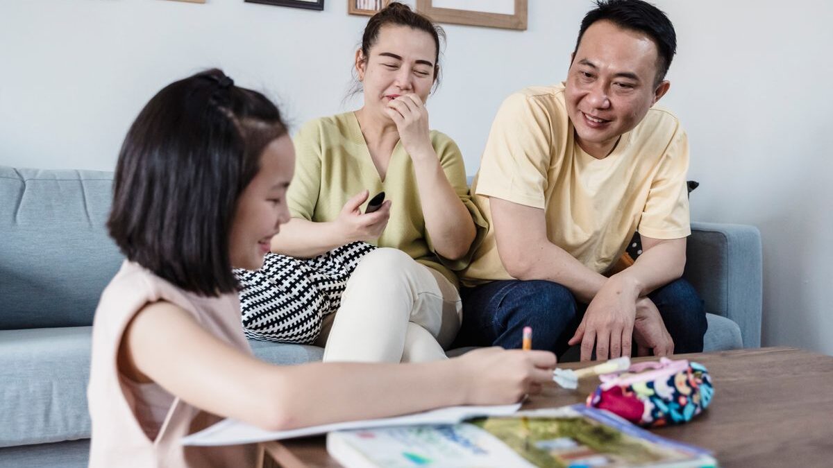 Niña mostrando su tarea a sus padres en la sala de su casa