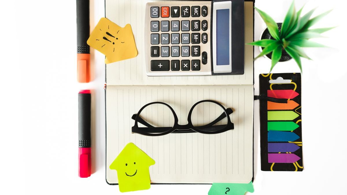 Calculadora, libreta y papelería sobre un escritorio, vista desde arriba