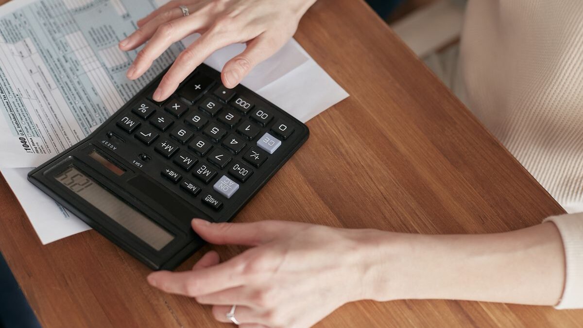 Mujer con una calculadora revisando sus facturas en casa
