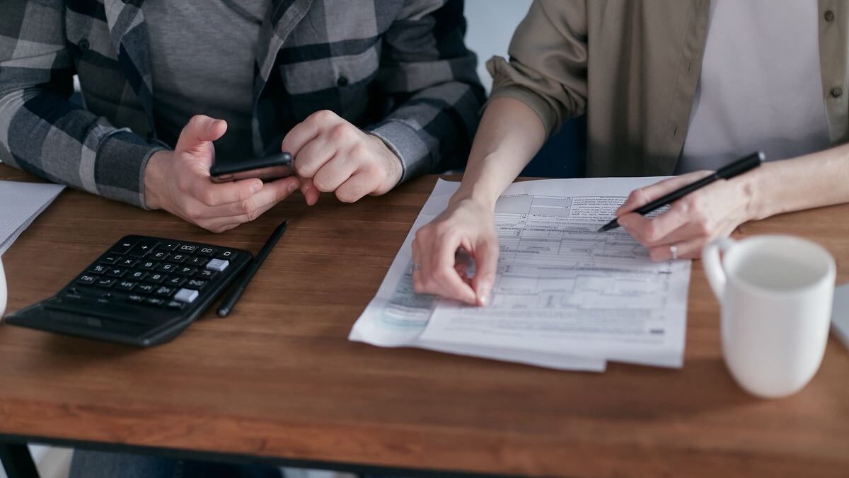 Pareja revisando sus finanzas con calculadora y documentos en casa