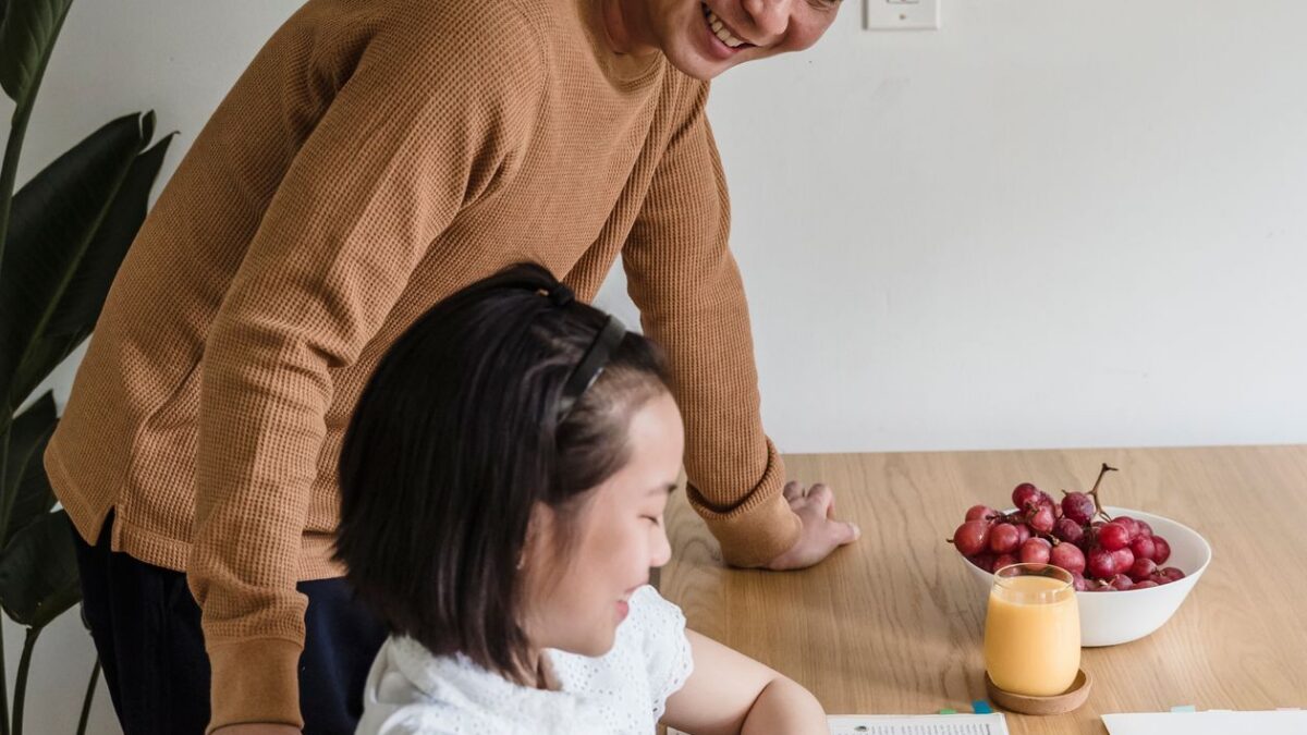 Padre ayudando a su hija con la tarea en una mesa